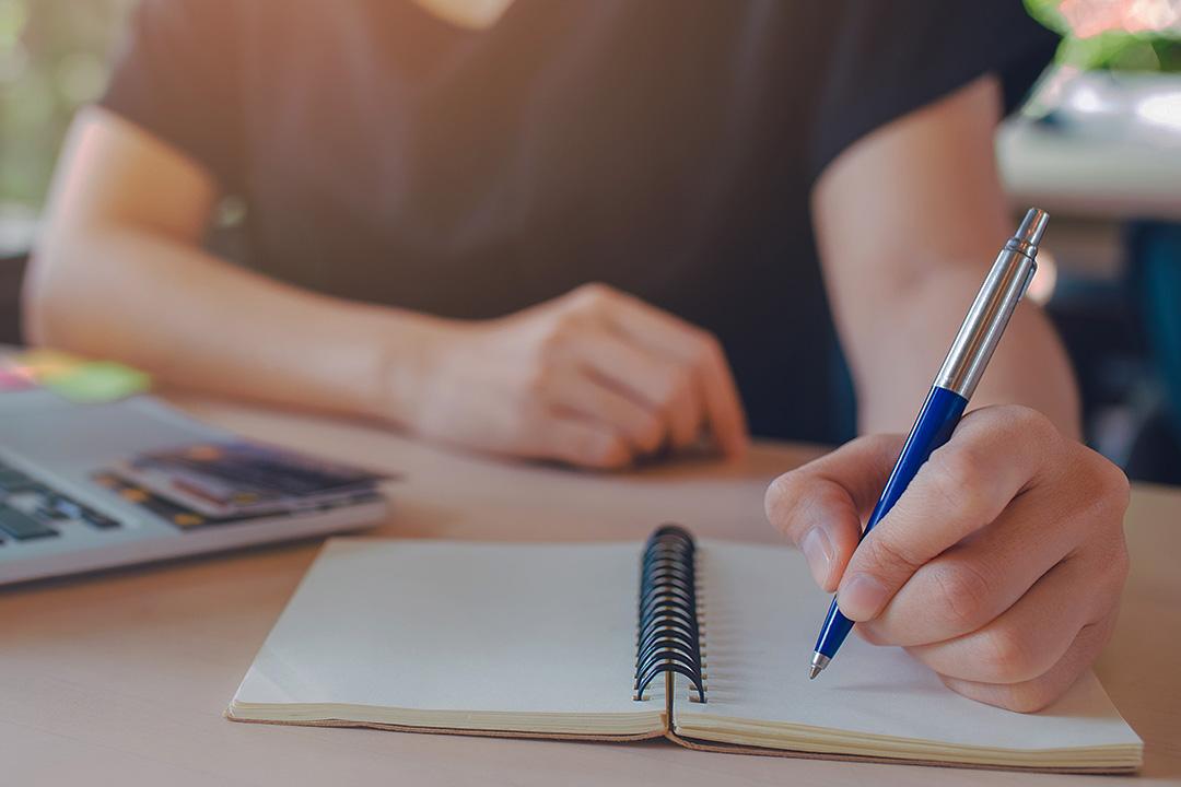 Business woman hand is writing on a notepad with a pen.Web banner.